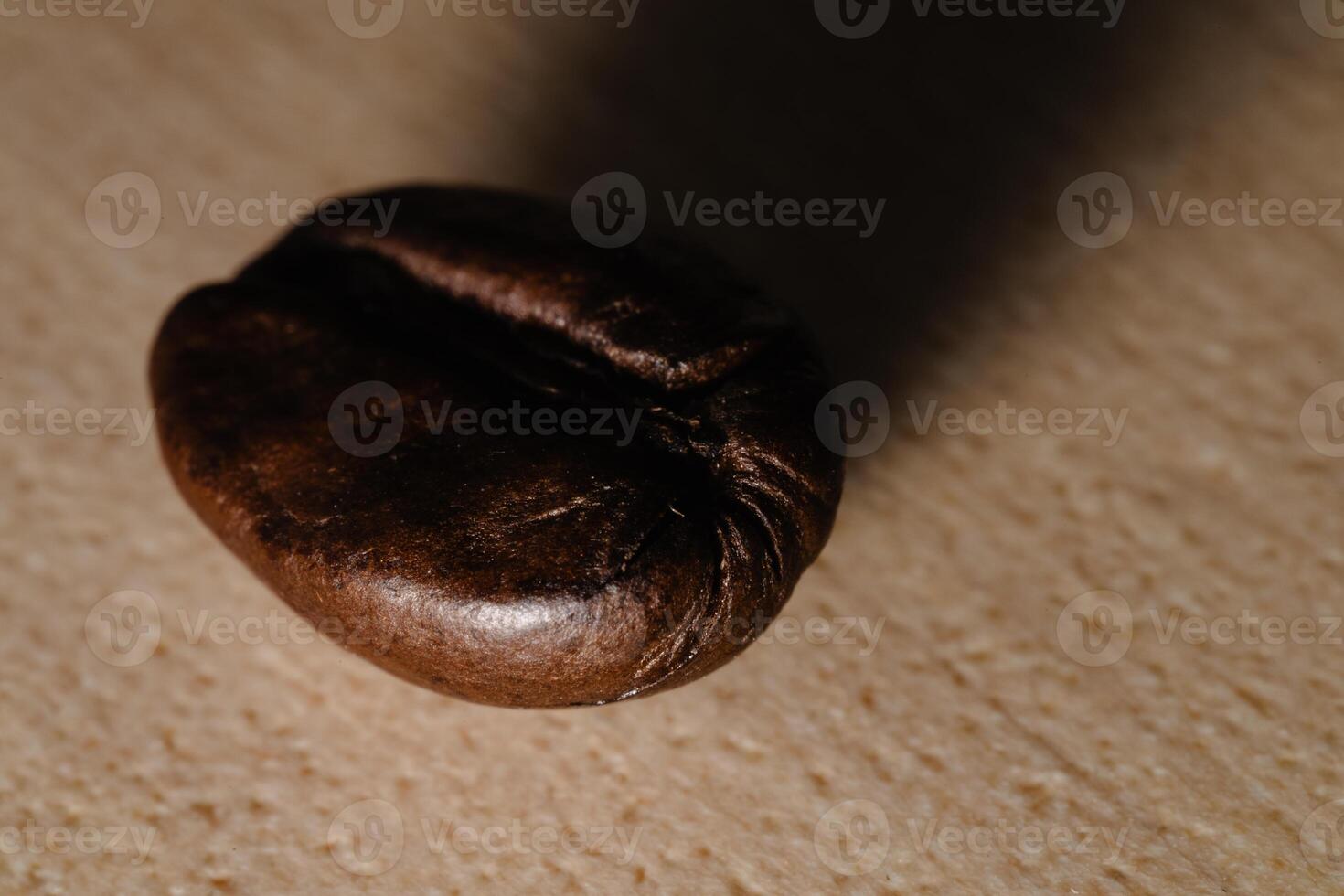 Close-Up of Dark Coffee Bean on Textured Surface with Shadows photo