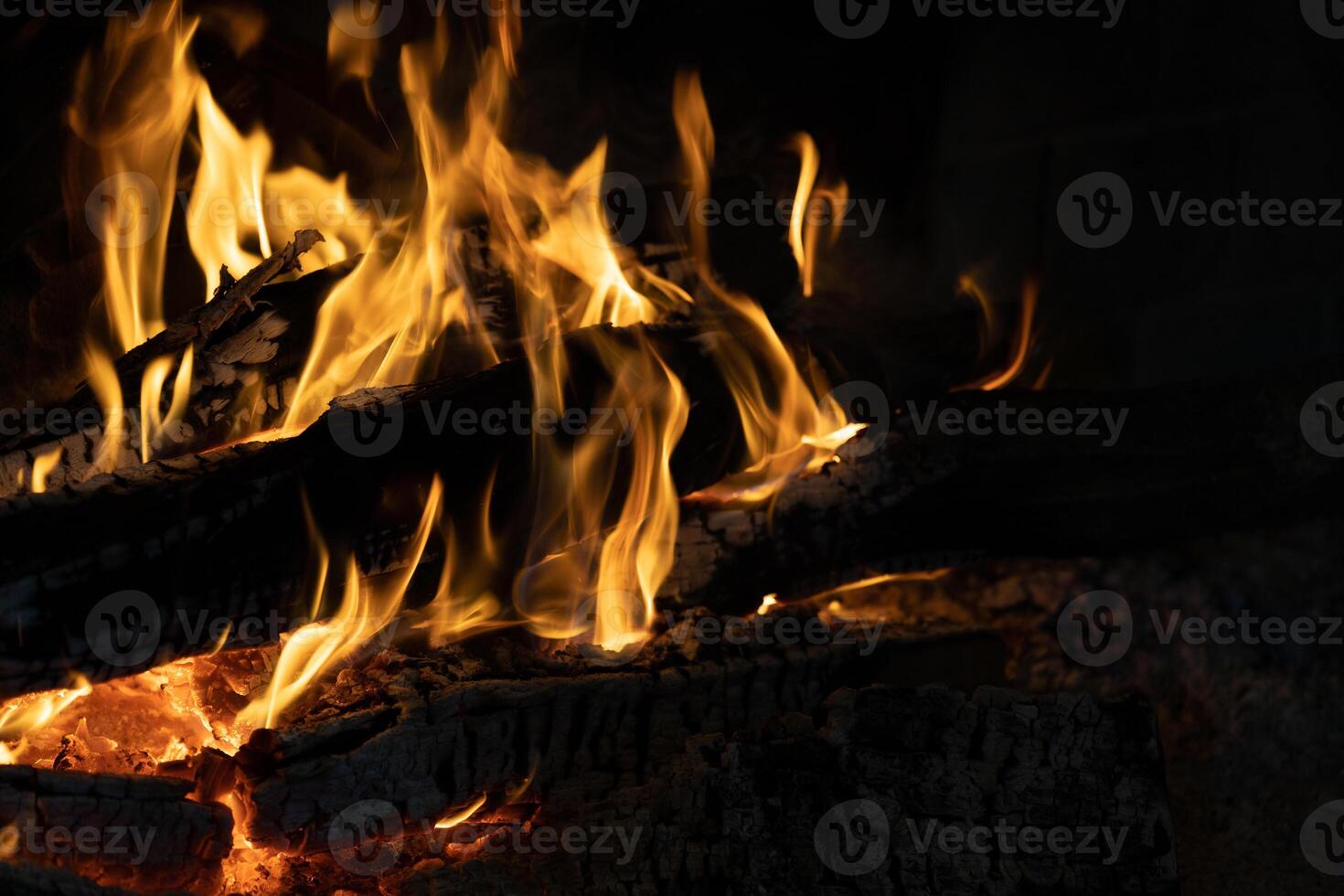 Intense Flames Engulfing Charring Logs in Dark Cozy Fireplace Setting photo