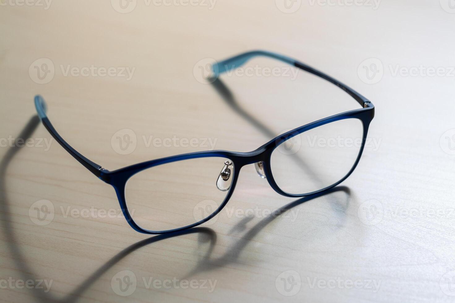 Close-up of stylish eyeglasses on wooden table indoor fashion photography photo