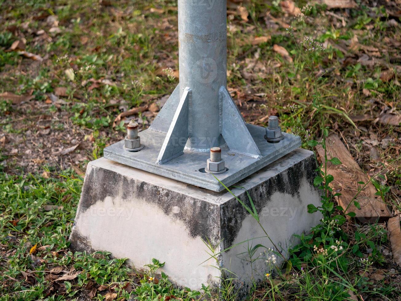 Metal pole structural base in industrial outdoor setting grass and ground level engineering photo