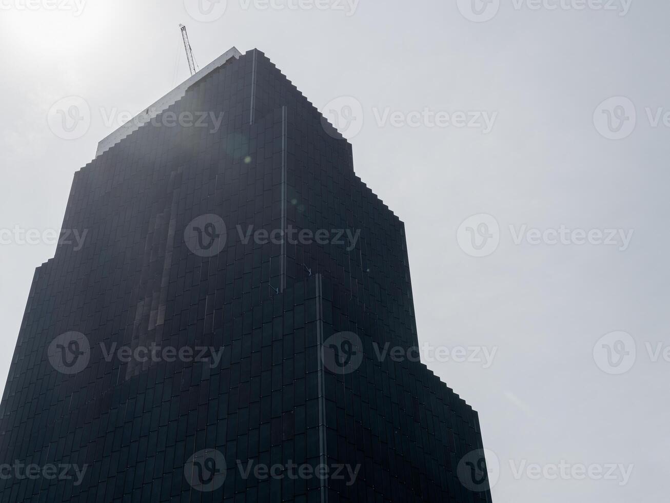 Skyscraper under mysterious fog urban city cloudy atmosphere low angle architectural design photo