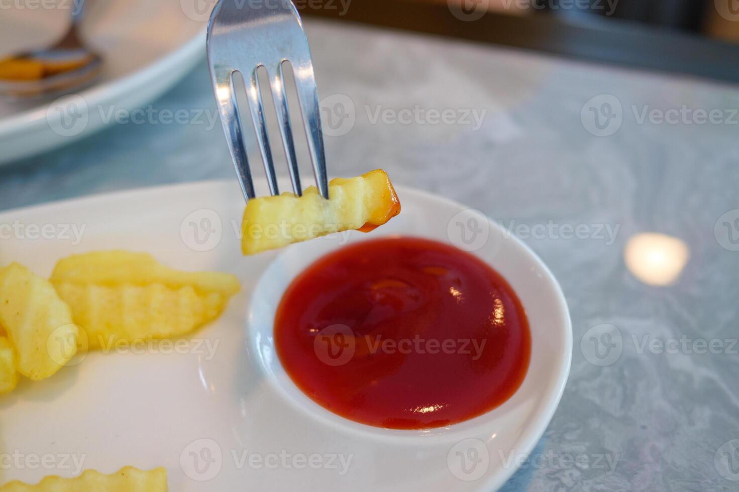 Delicious crinkle-cut fries dipped in ketchup restaurant table food casual setting photo