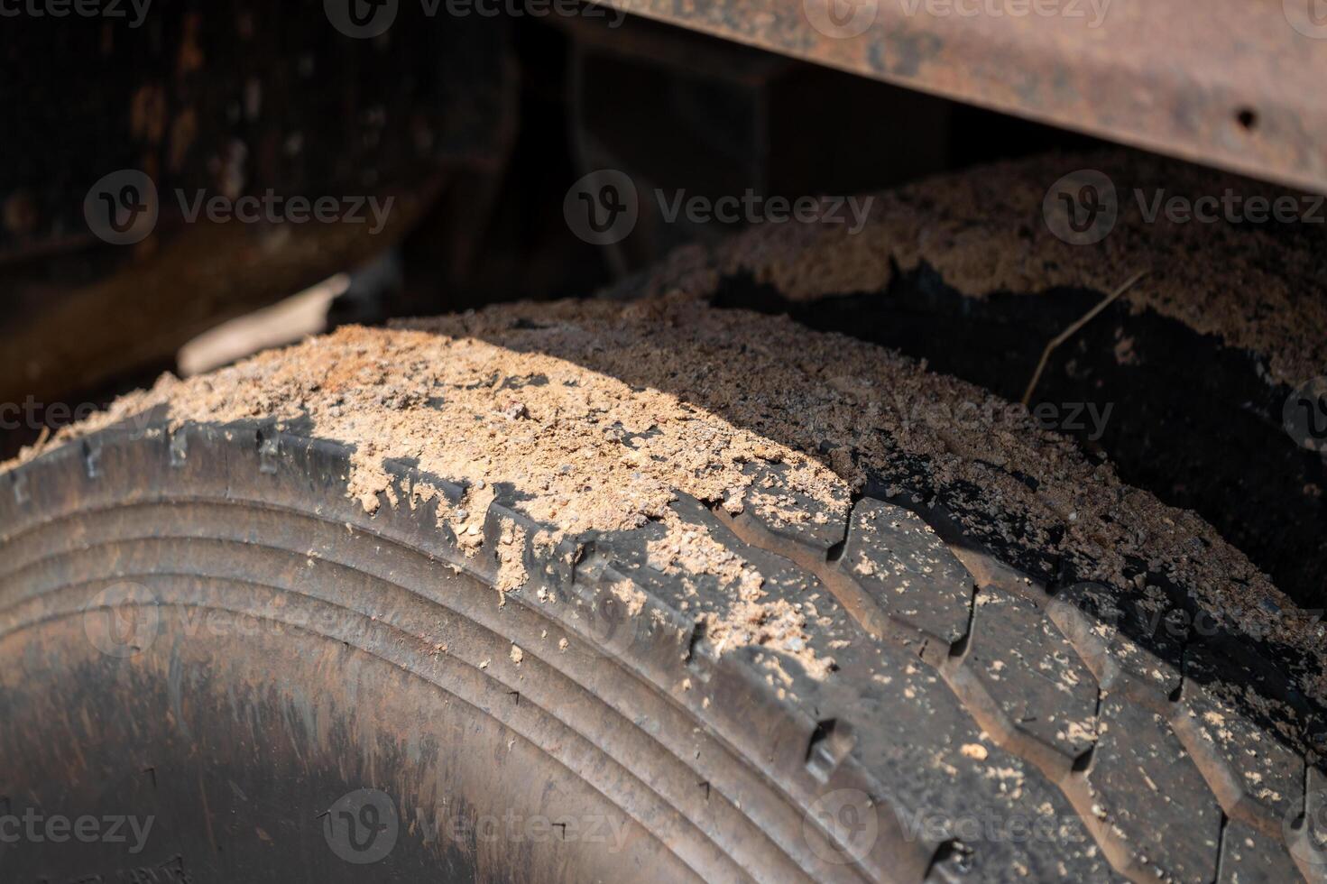 Ground level image of worn-out truck tire in dusty industrial environment - transport focus photo
