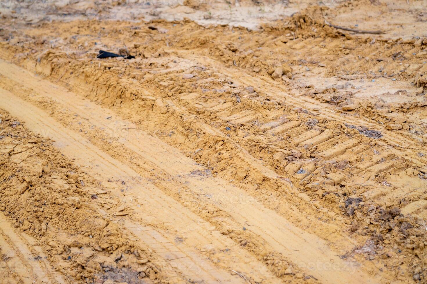 Close-up of soft sand construction site with heavy machinery tracks - industrial ground texture photo