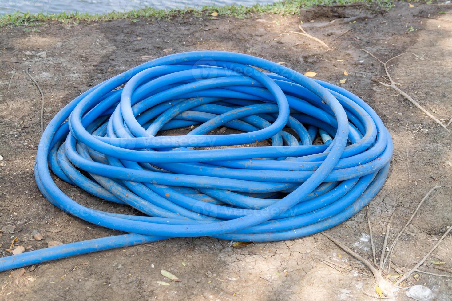 Blue garden hose coiled ground outdoor setting nature close-up watering concept photo