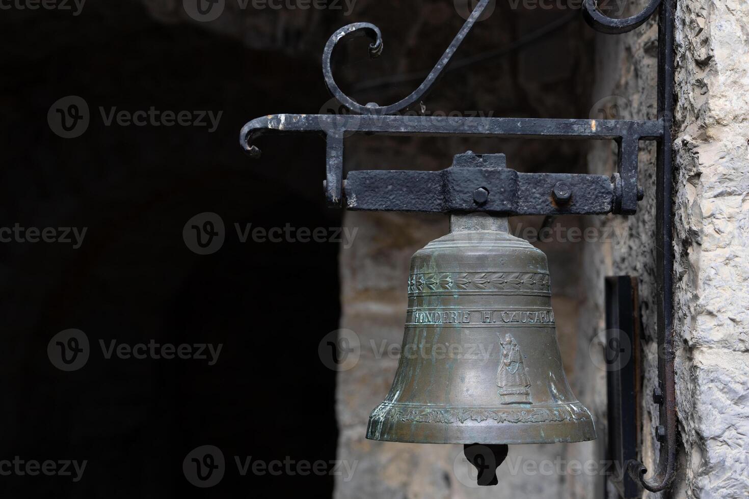 Rustic Bronze Bell Mounted on Weathered Stone Wall in Historical Setting photo