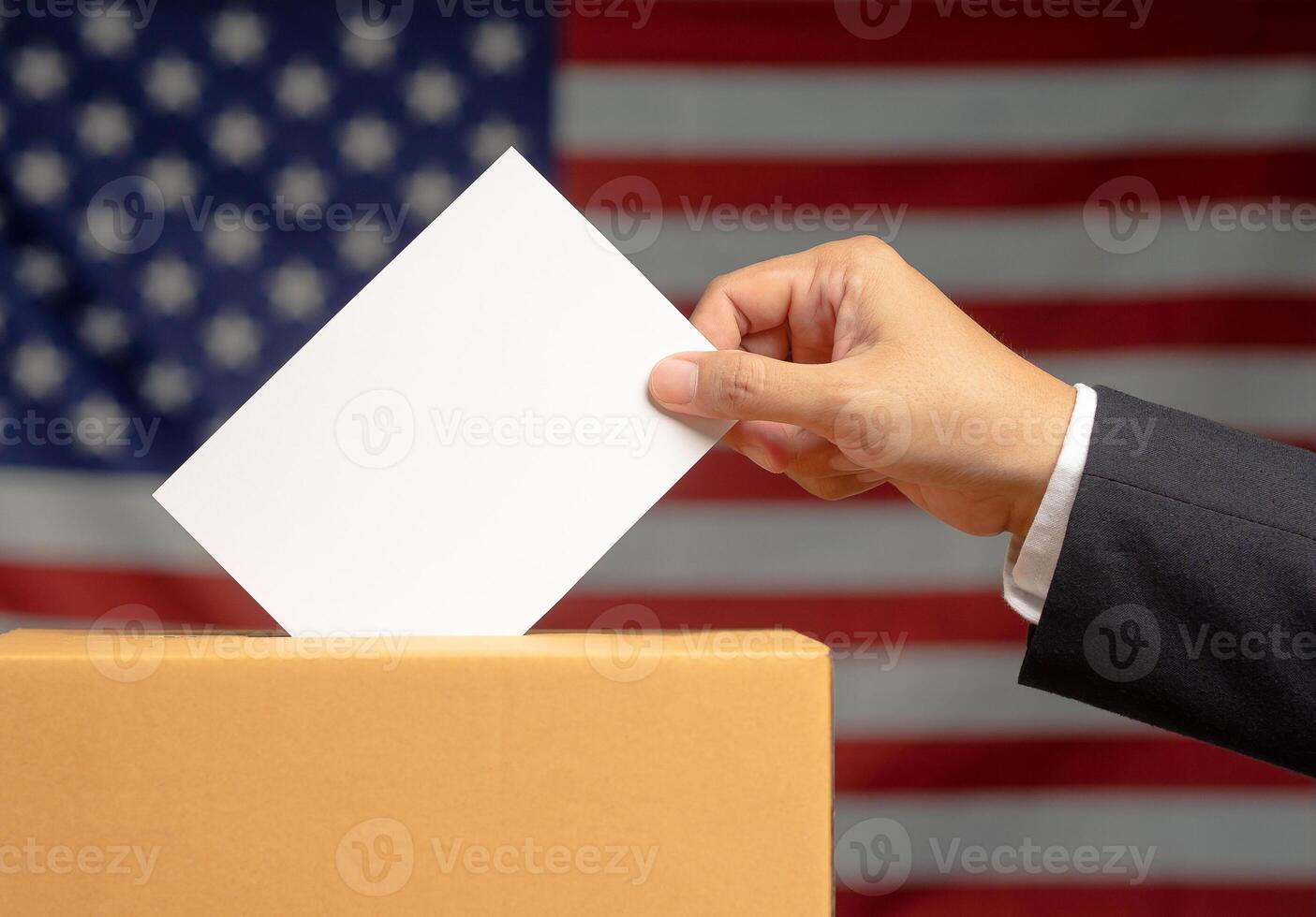 Hand voter holding ballot paper putting into the voting box at place election against the American flag background photo