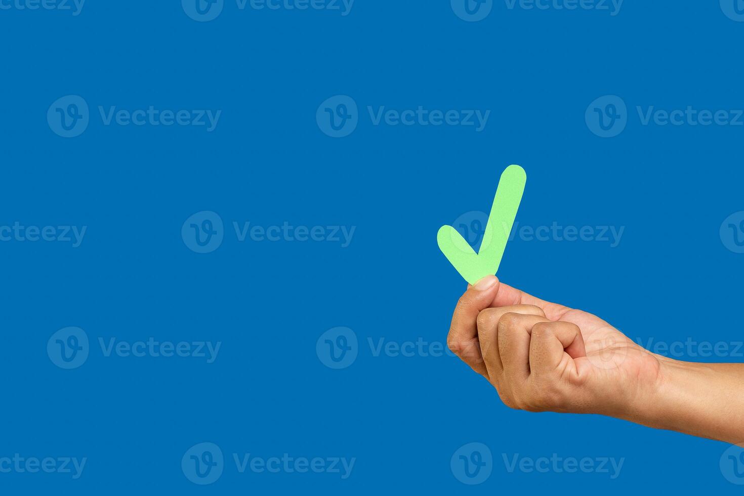 Hand holding a green check mark symbol against a blue background. photo