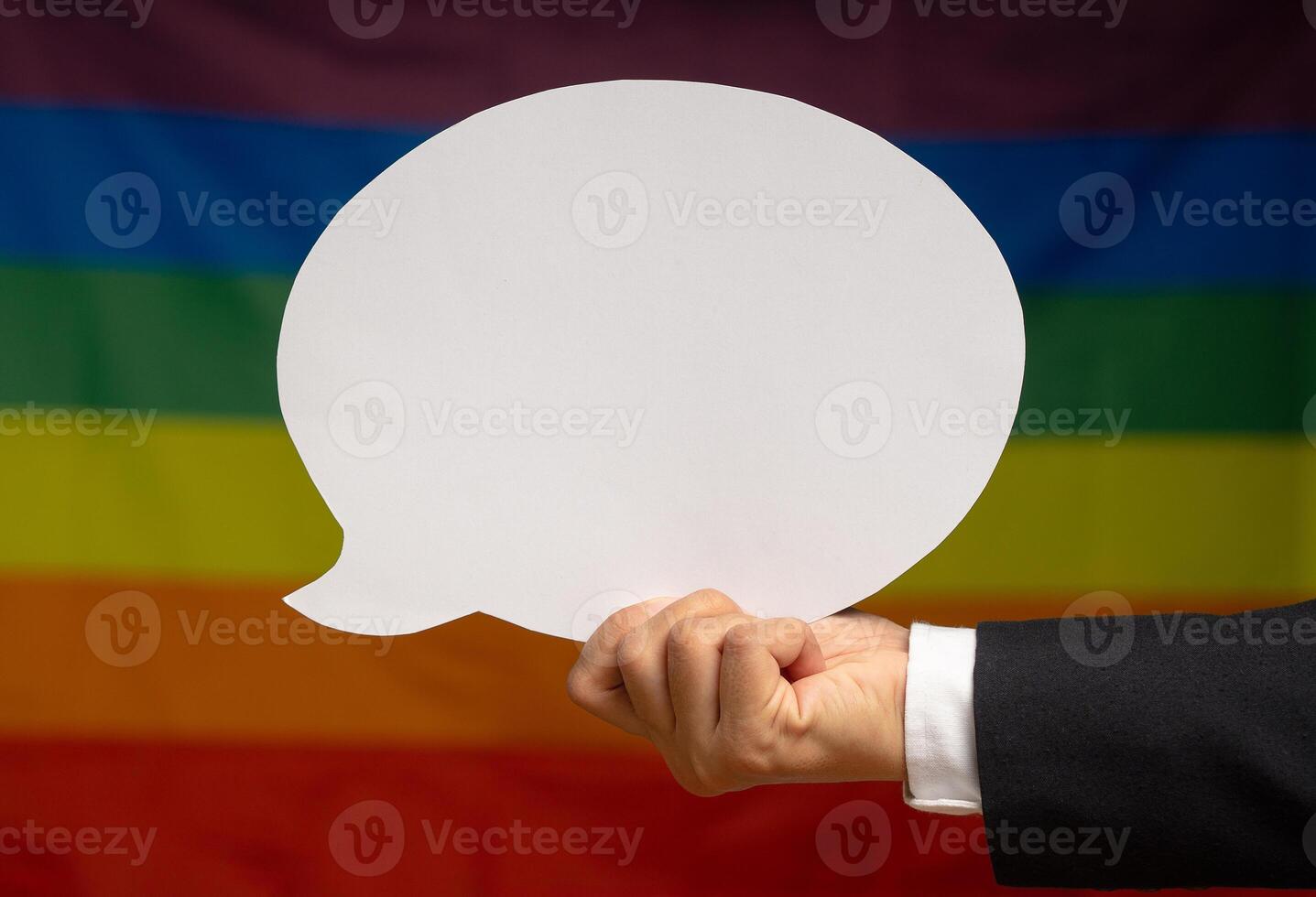 Hand holding a white speech bubble against a rainbow flag or LGBT flag background photo
