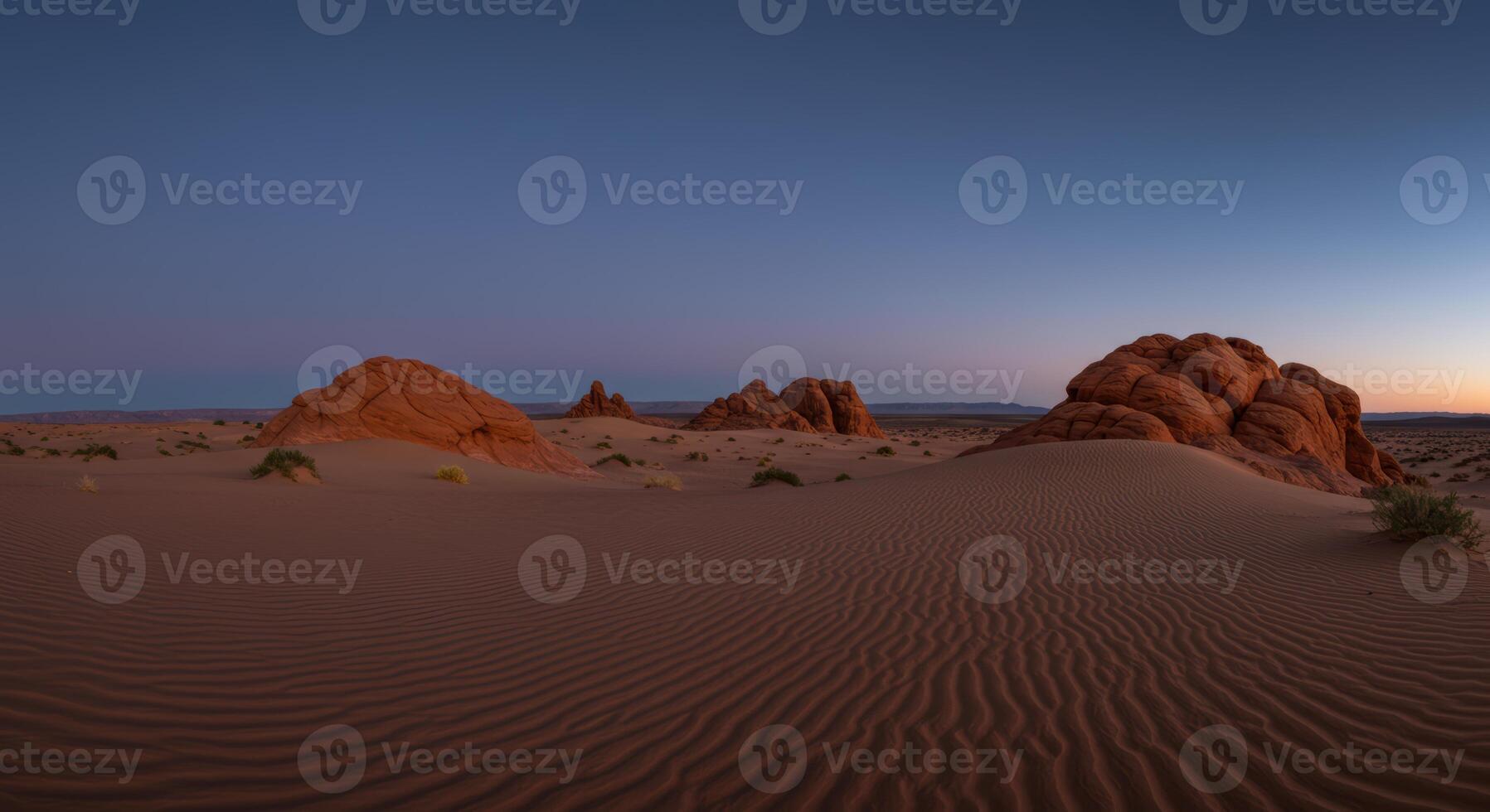 Picturesque desert scenery featuring rippled sand dunes and unique rock formations under a twilight sky photo