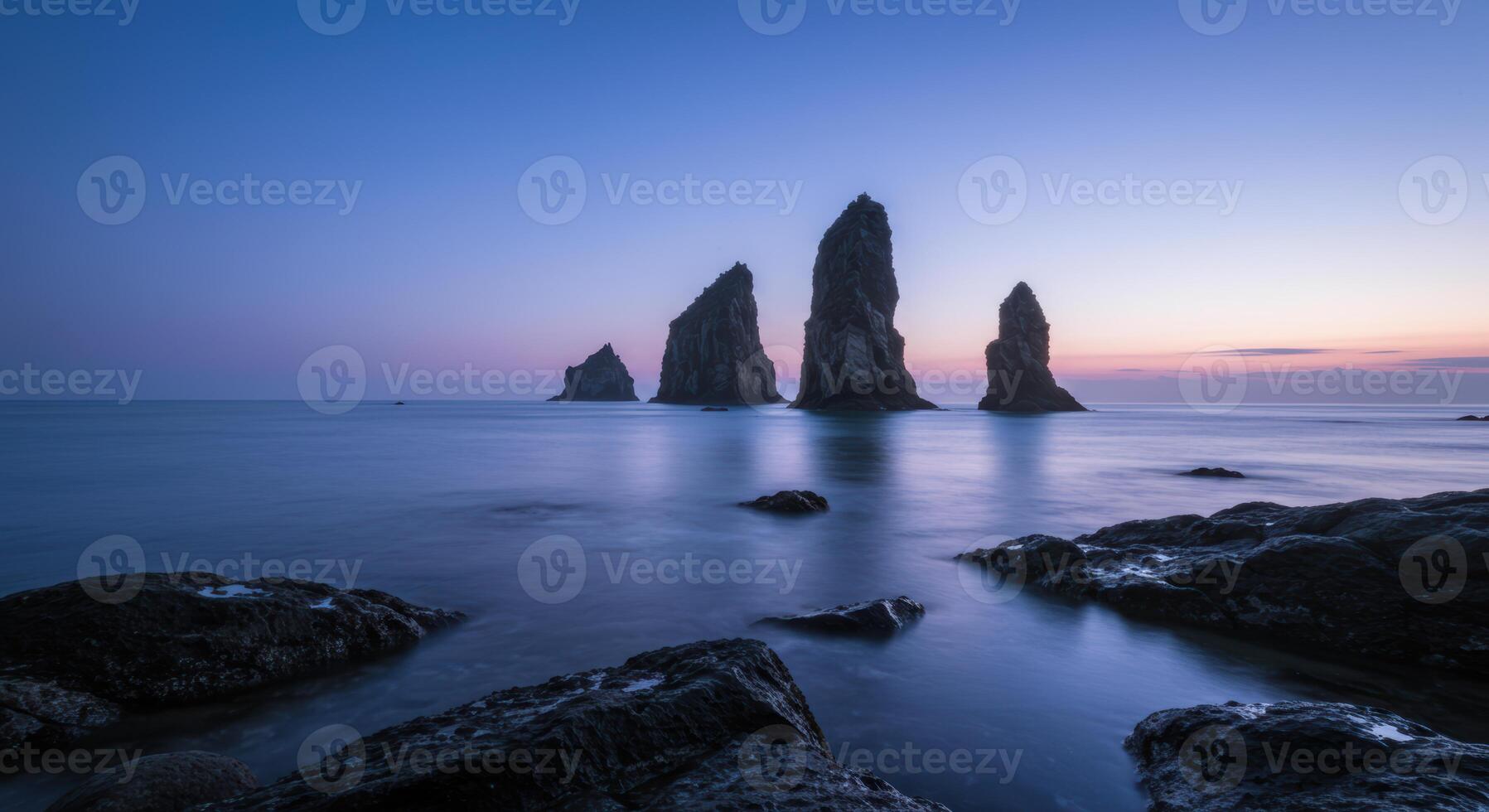 Serene ocean landscape featuring dramatic rock formations under a twilight sky creating a peaceful and scenic view photo