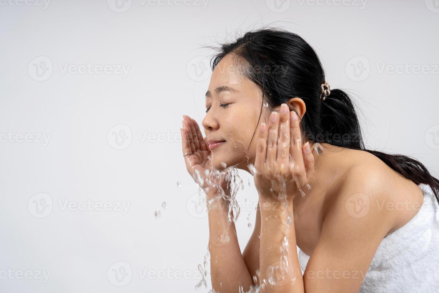 Attractive woman washing face on white background photo