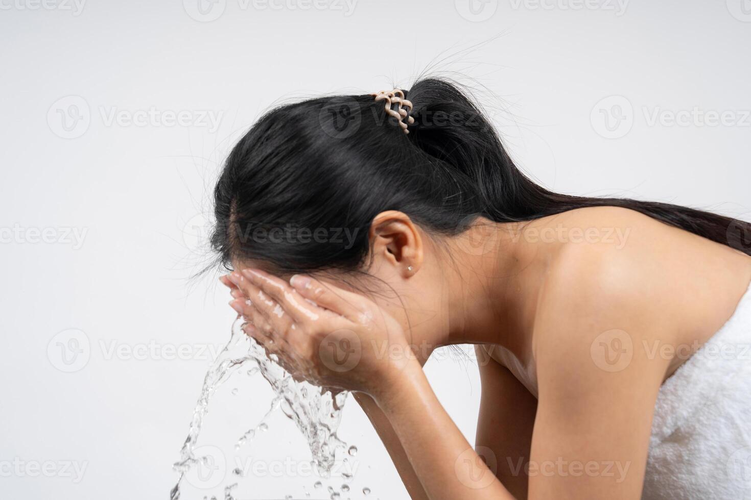 Beautiful woman wearing white towel after shower, washing face with water photo