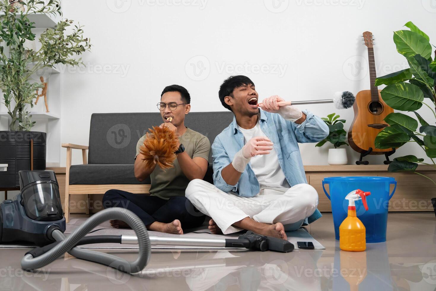 Fun Cleaning Session with Friends. Two young men enjoying music while cleaning their home. photo