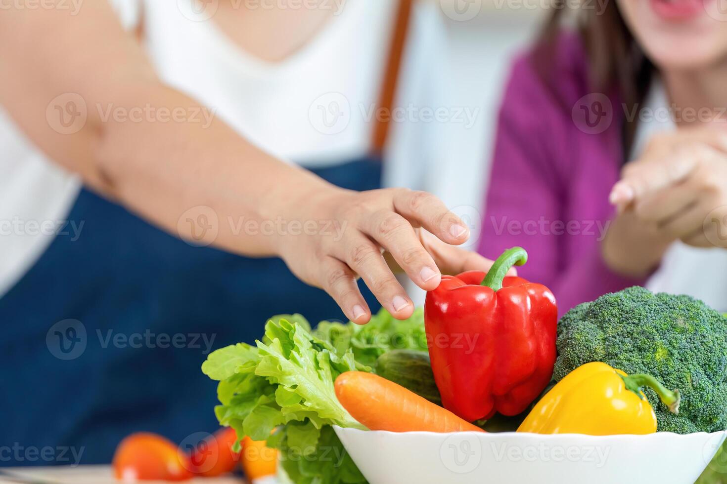 Healthy Cooking Together. Close-up of hands reaching for fresh vegetables in a kitchen. photo