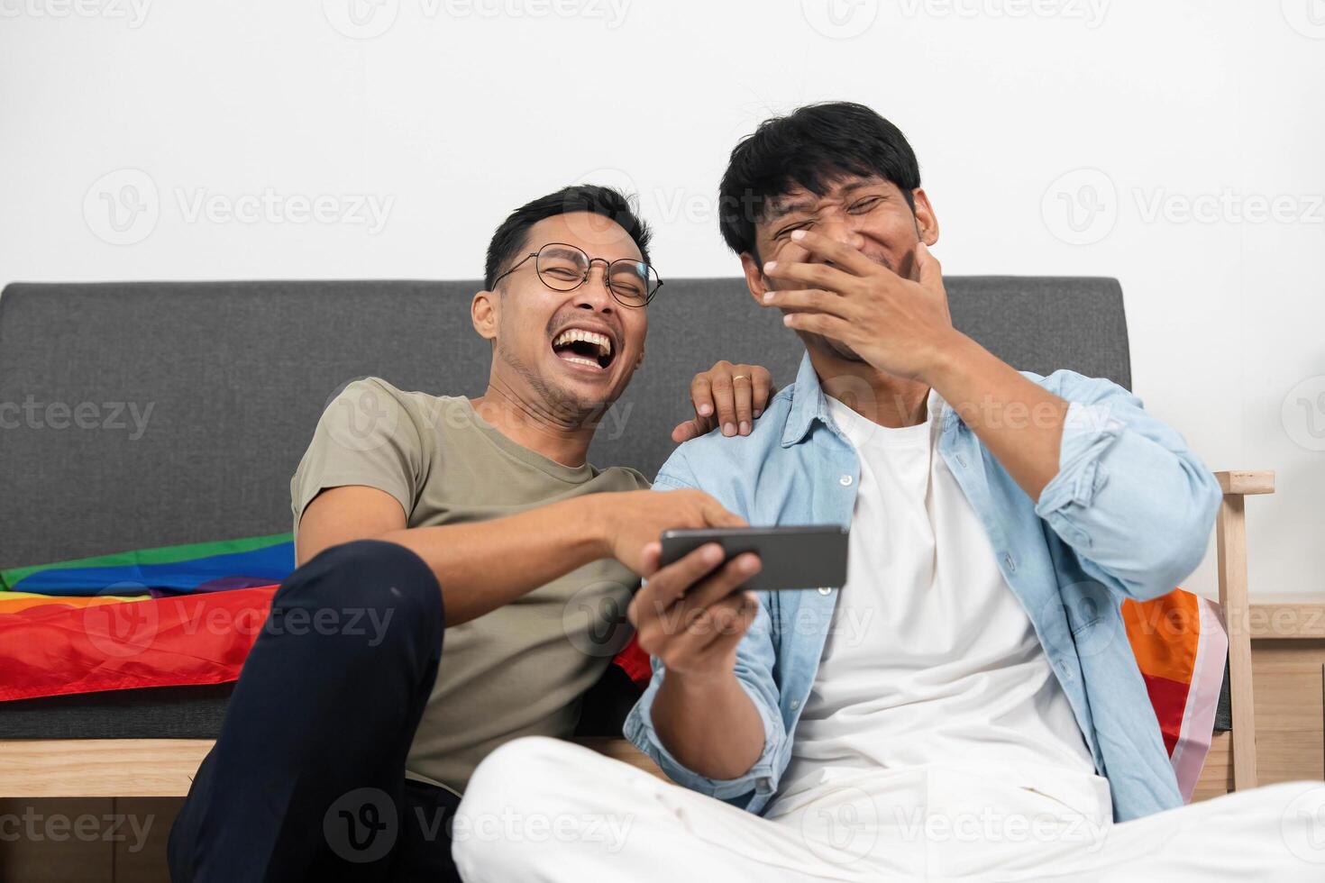 LGBTQIA Couple Sharing Laughter. Two young men enjoying a funny moment while watching something on their phone. photo