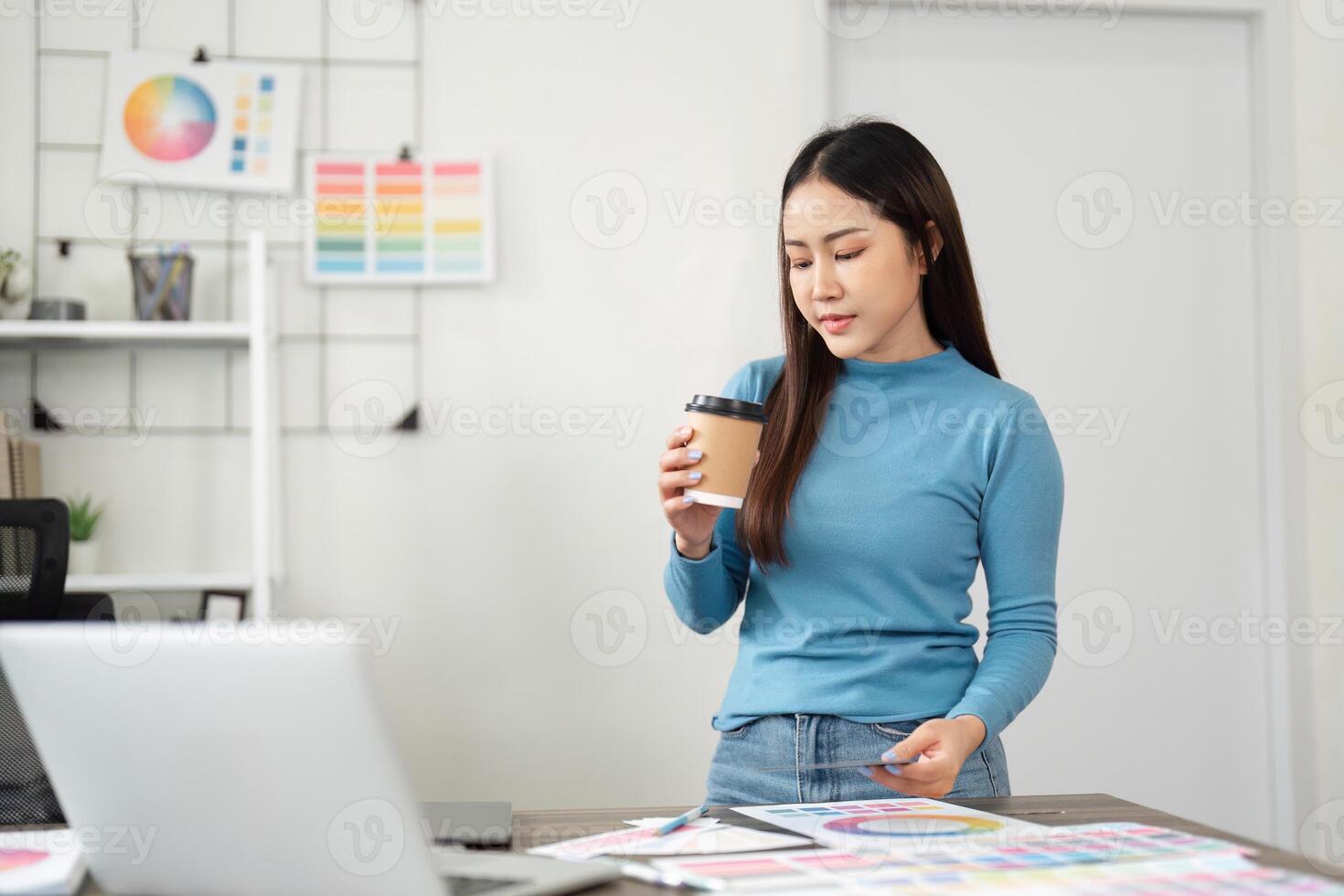 Coffee and Creative Work. A designer enjoys her coffee while evaluating design samples in her workspace. photo