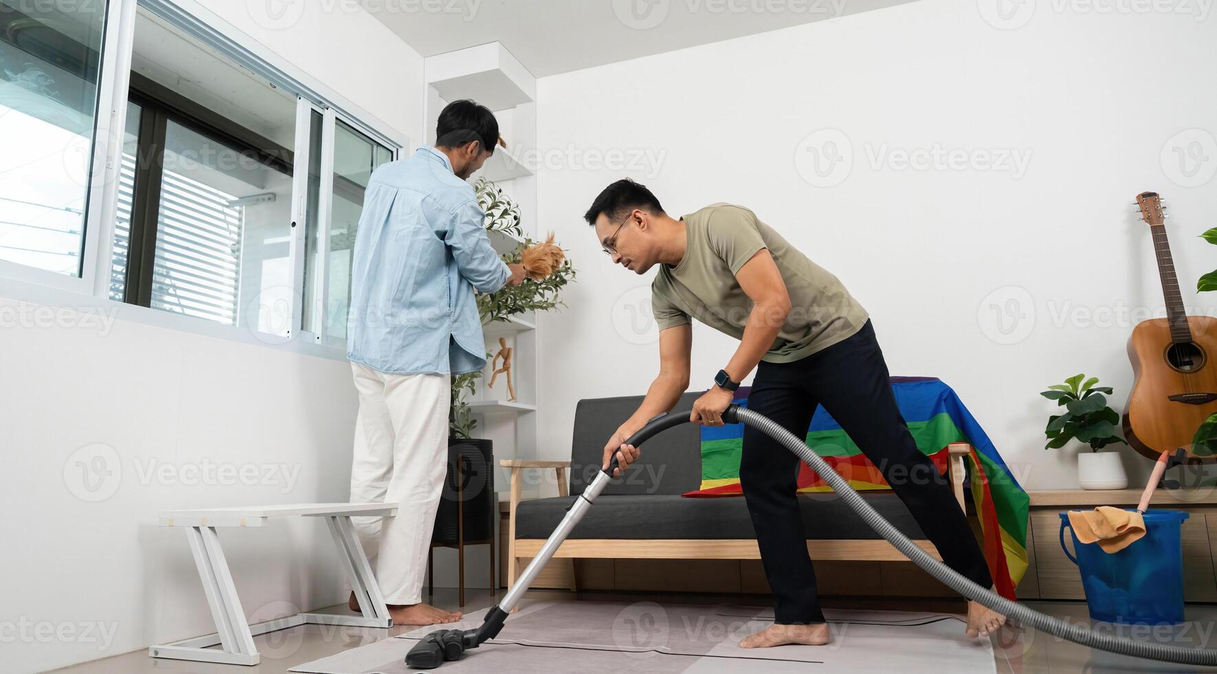 Collaborative Home Cleaning and LGBTQIA Pride. Friends vacuuming and decorating a vibrant space. photo