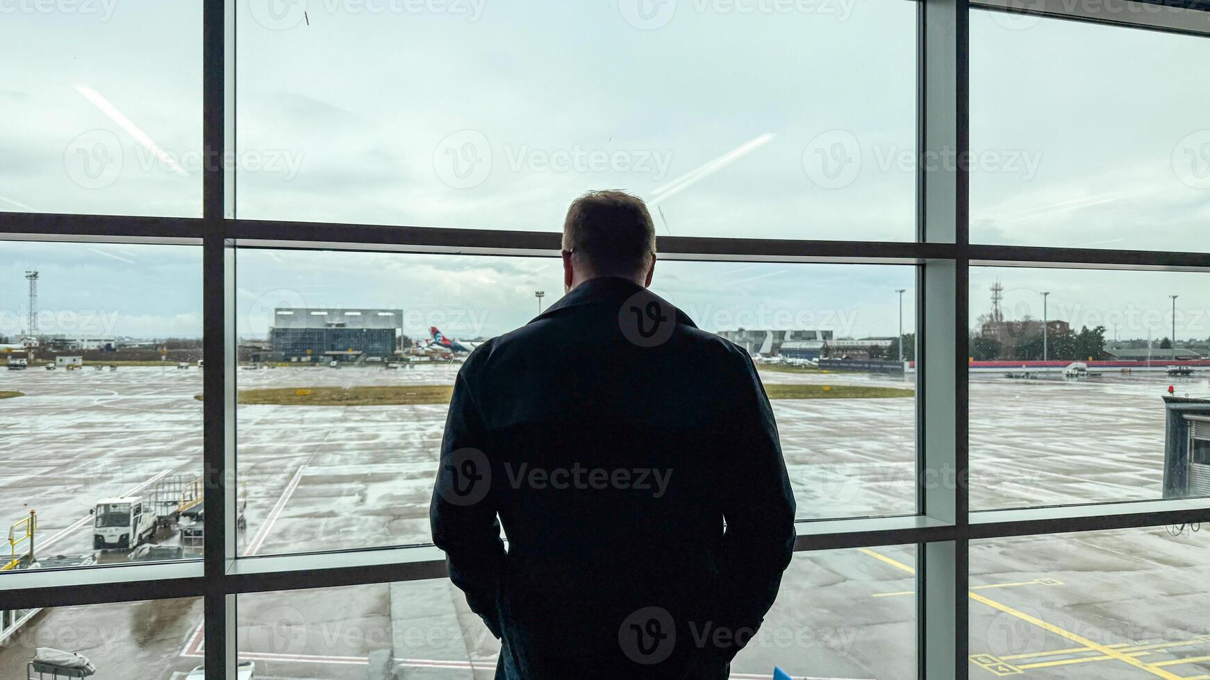 Gazing at the rain soaked tarmac, a contemplative Caucasian man dreams of distant horizons reminiscent of International Day of Friendship and Wanderlust Festival photo