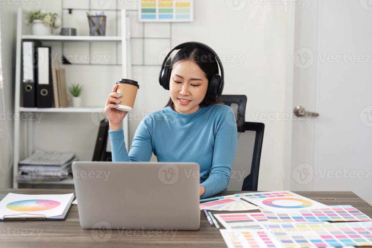 Focused Work and Multitasking. A designer works on their laptop and listens to music while enjoying a coffee break. photo