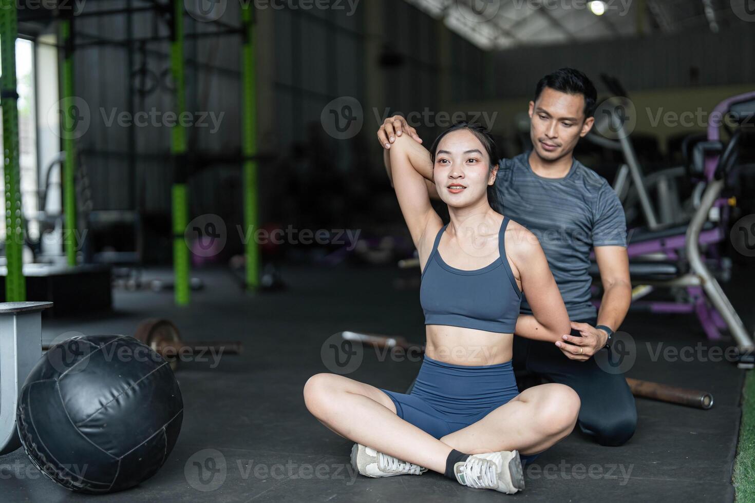 Personal Training and Fitness Coaching. A trainer assisting a woman with stretching exercises in a gym. photo