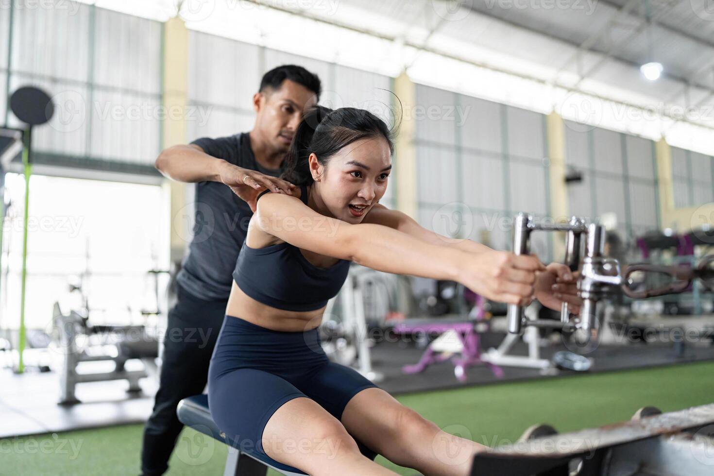 Personal Trainer Assisting Client with Rowing Machine Exercise photo