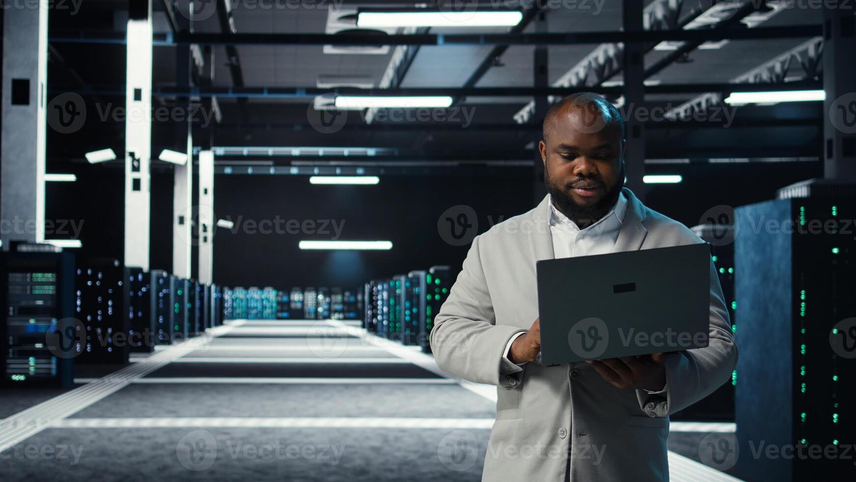 Data center engineer coding on laptop, doing software updates for mainframes. Server farm IT professional typing on notebook keyboard, optimizing infrastructure, camera A photo