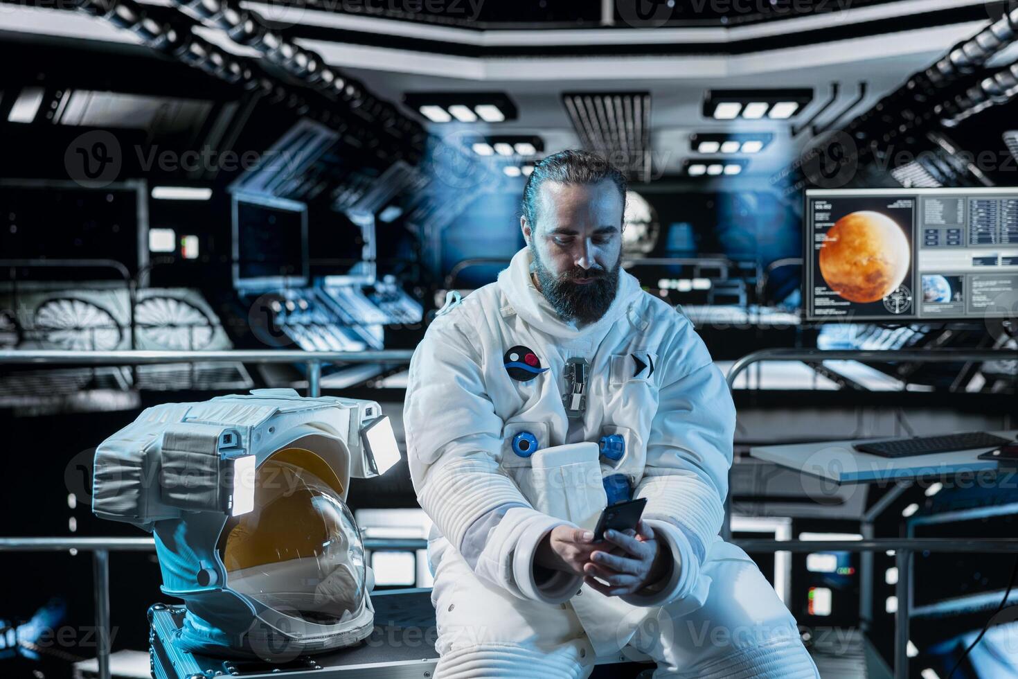 Lonely astronaut using smartphone to text friends before landing spaceship on Mars. Isolated man using phone to chat with family during mission to red planet surface in deep space photo