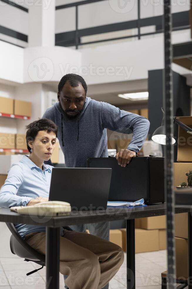 Team of diverse workers reviewing custom orders in a distribution hub filled with taped boxes on shelves or racks, People representing a local brand small scale logistics center. photo