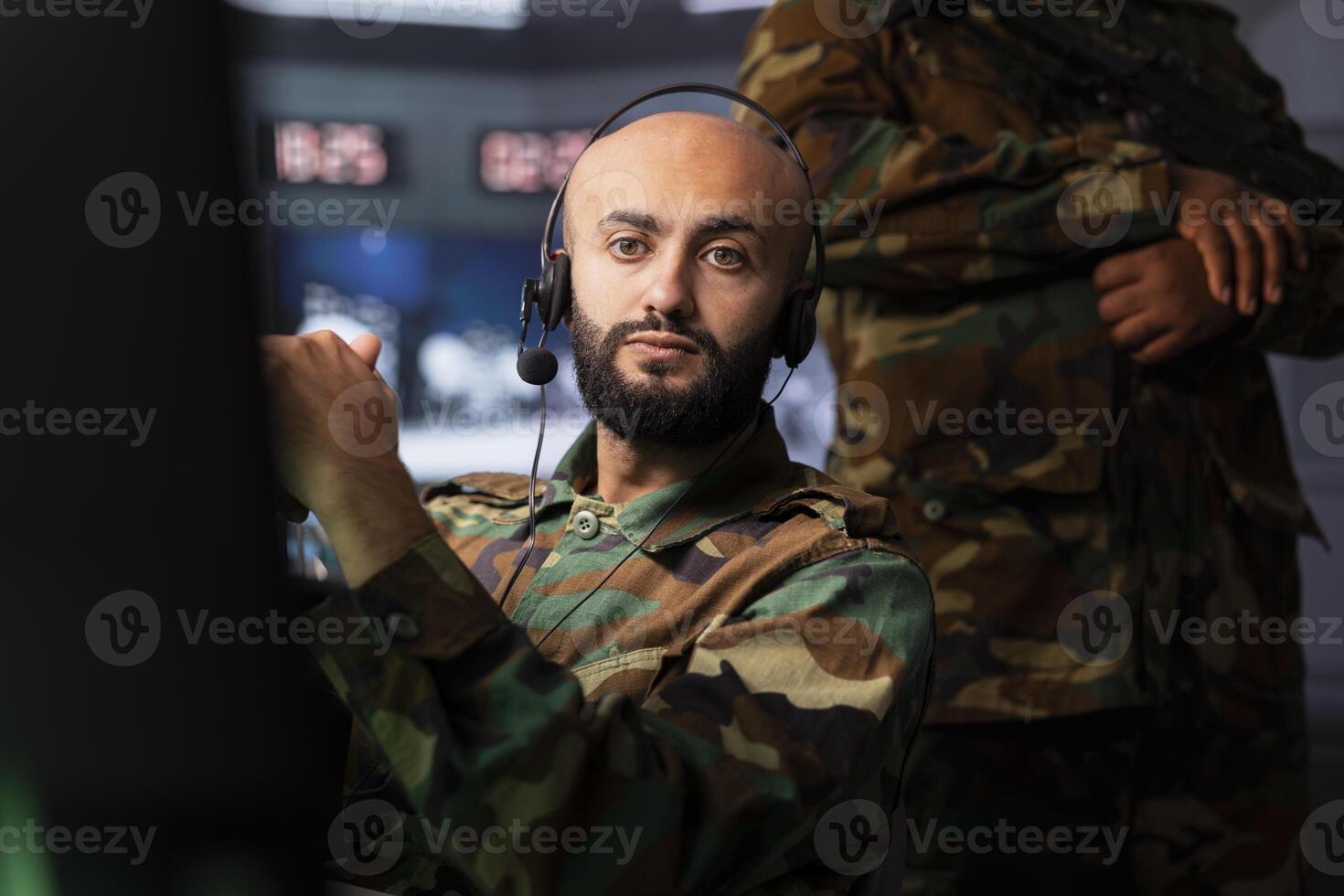 Military agent in war room doing reconnaissance mission, using headset gear. Army expert monitoring counterinsurgency enemy fighters using telecommunication systems to intercept calls photo