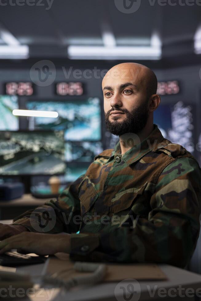 Air force combat control officer performing tactical level surveillance in headquarters, using satellite equipment. Military expert using radar technology to search for potential assault zones photo