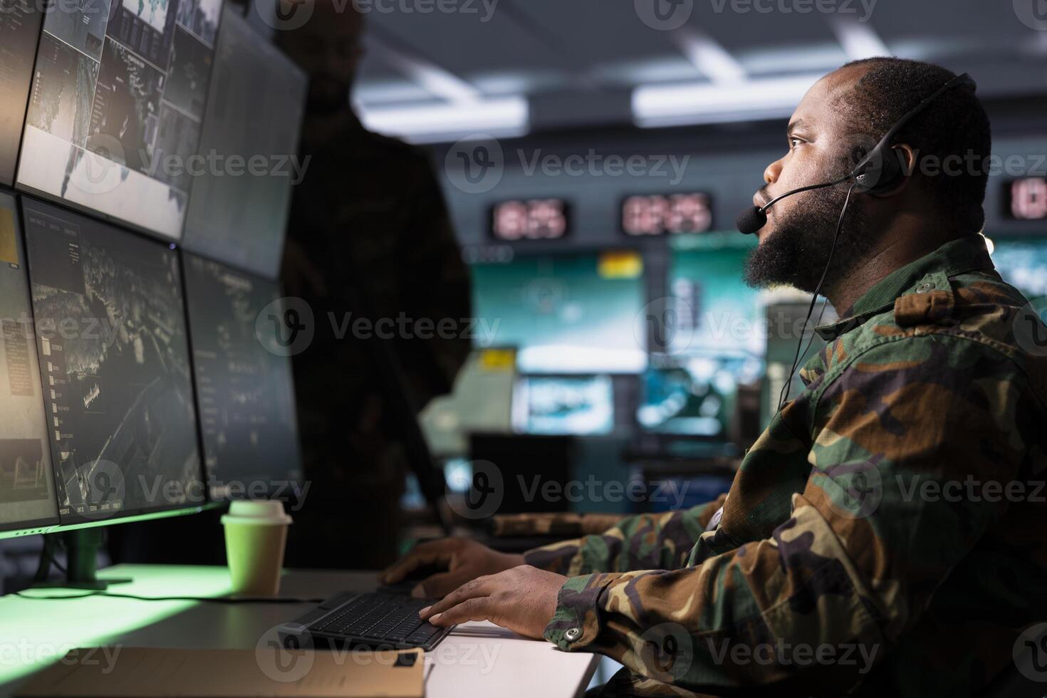 Soldier conducing anti terrorism mission in base of operations employing radar systems to detect and track enemy aircraft. African american specialist studying satellite CCTV visualization photo