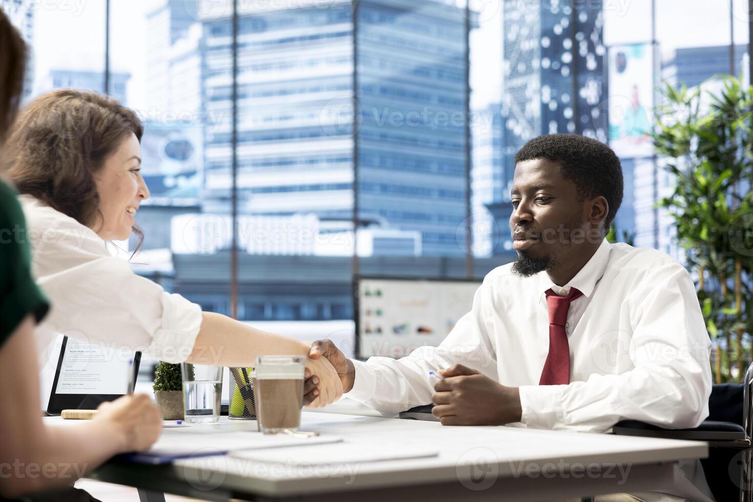 HR manager finishing deal with person with paraplegia after finishing background checks to job applicant. HR professional doing handshake with man with impairment earning position photo