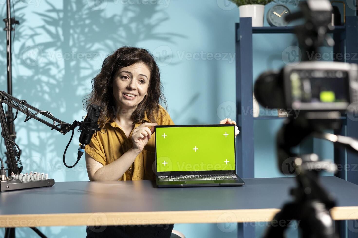 Cheerful woman in studio filming tech tutorial on how to do maintenance on broken chroma key laptop. Jolly online show host teaching subscribers how to open and fix defective green screen notebook photo