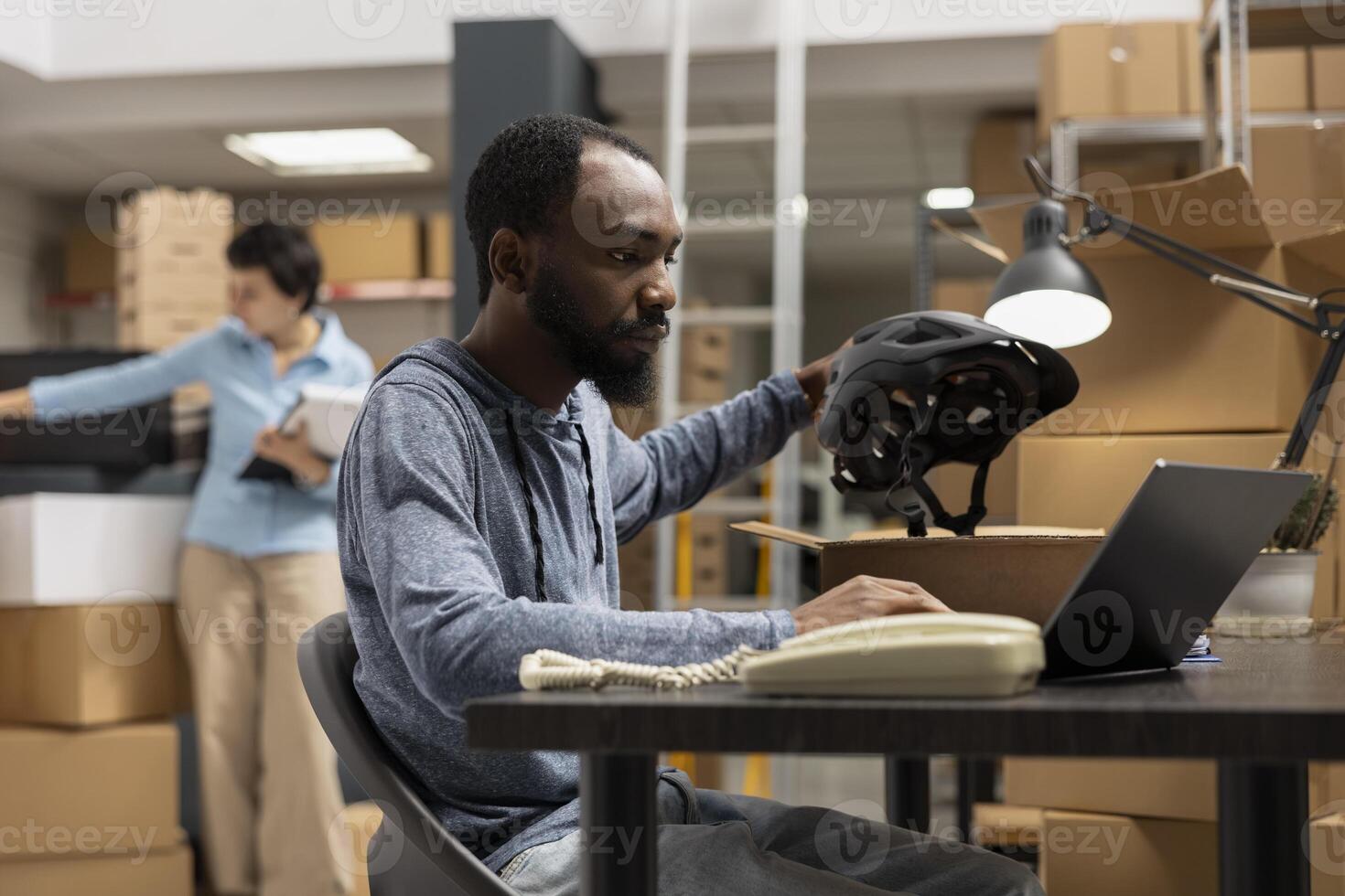 African american guy managing product handling and packing goods for distribution in a logistics center, working on custom orders from the shipping area at the warehouse depot. photo