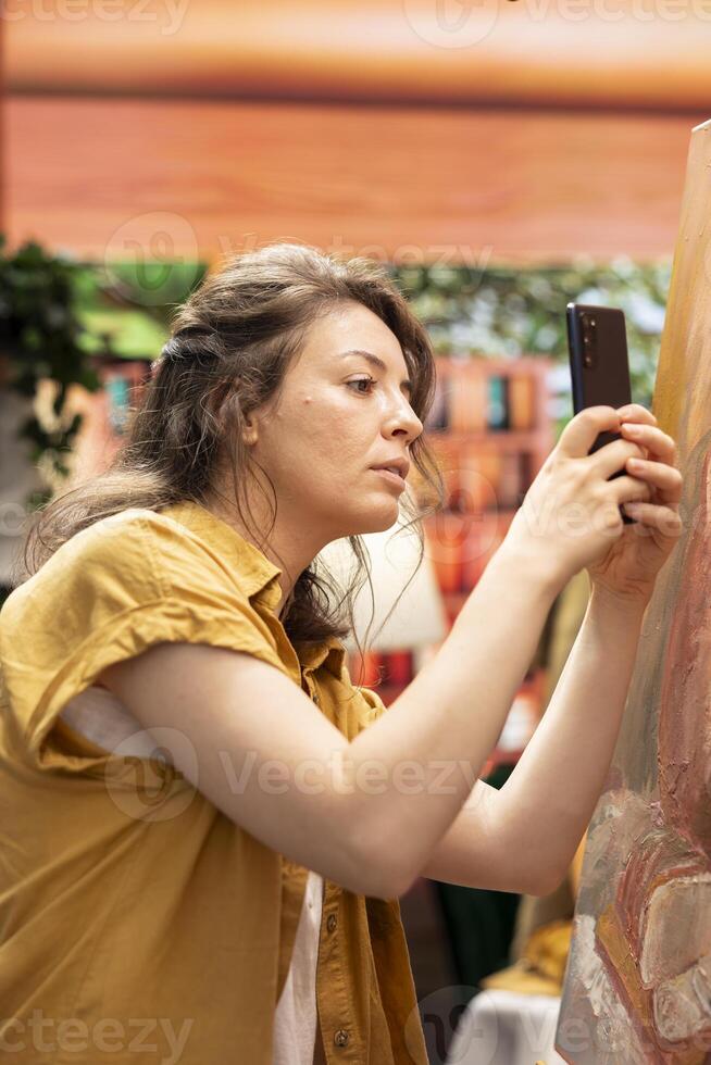 Woman painter recording a vlog to advertise her painting on social media channel, creating a self promotion for better reach and engagement. Artist advertising her masterpiece for audience. photo