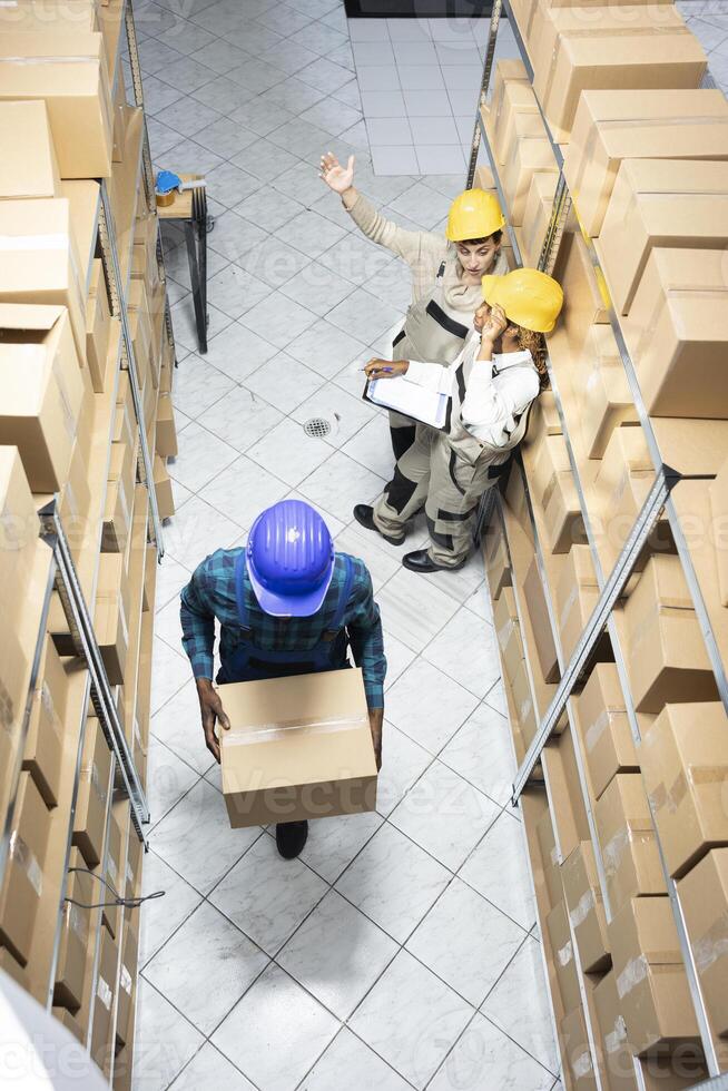 Diverse employees group preparing parcels and managing stock in an organized warehouse depot facility. Logistics center staff supports retail distribution and operational effectiveness. photo