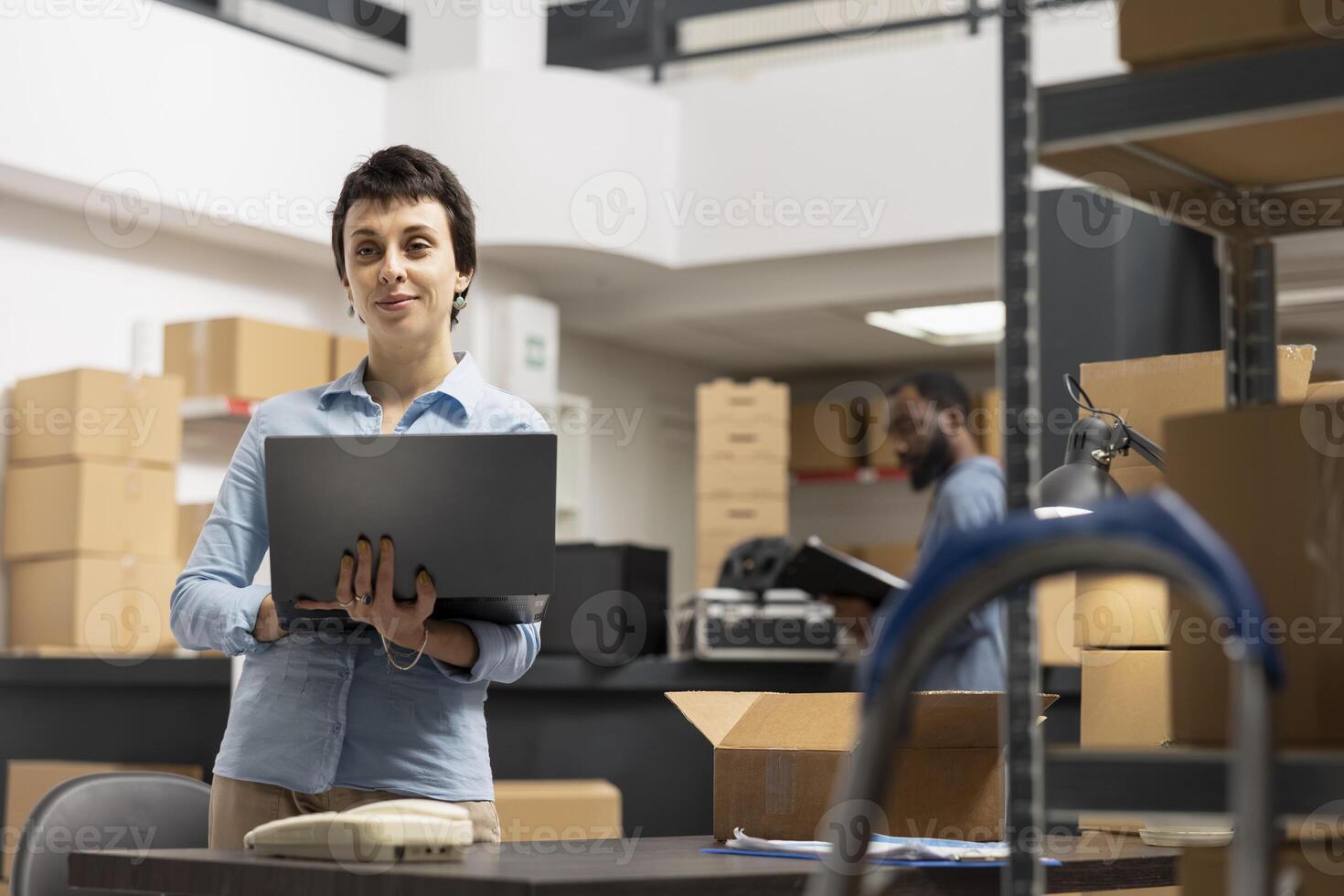 Woman employee working in a warehouse on order processing in small business depot, preparing taped boxes for local brand express delivery logistics. Distribution center supply room. photo