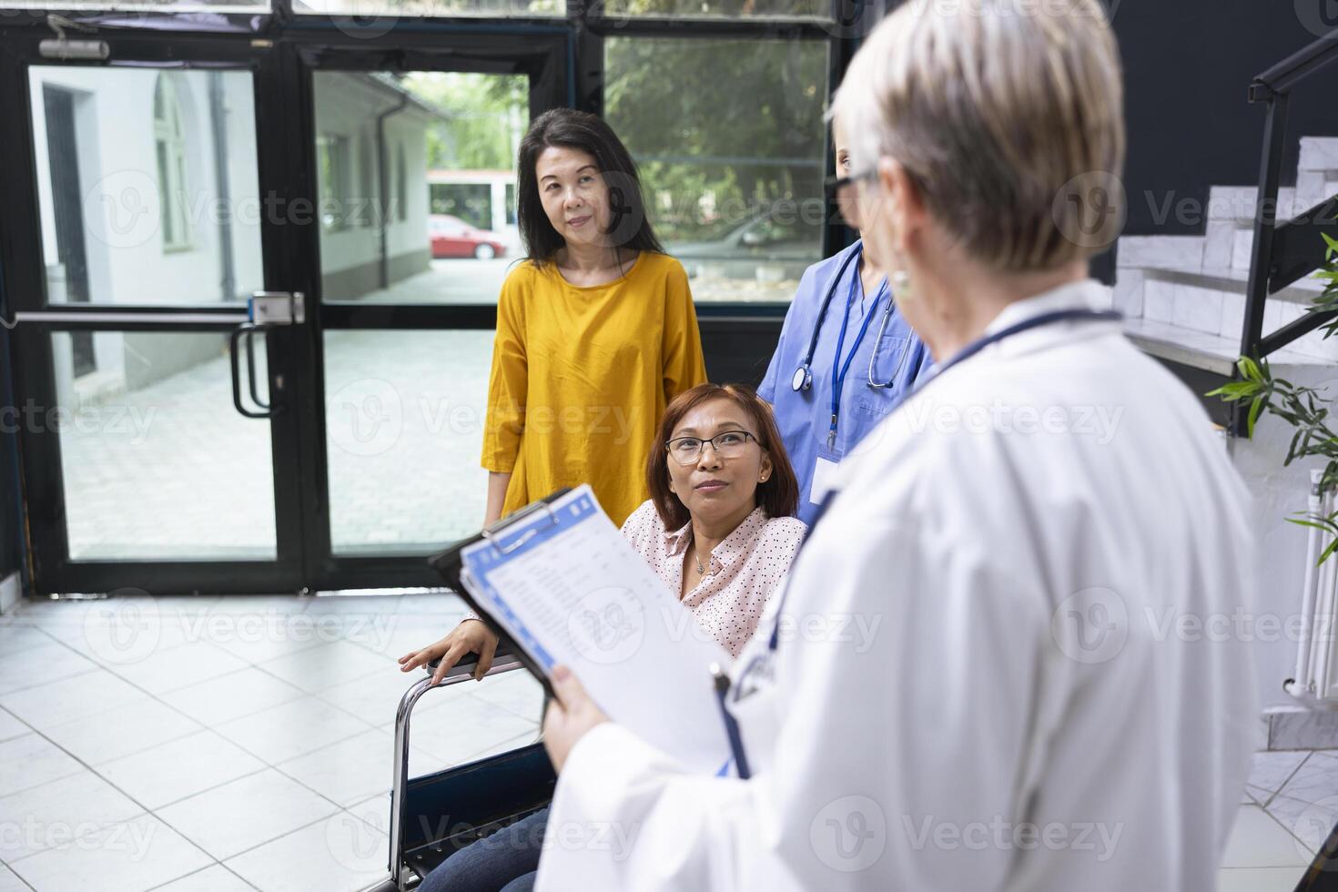 Wheelchair user discussing with medic at routine checkup at the clinic, offering guidance and assistance while discussing medical condition care for physical disability. Health check. photo