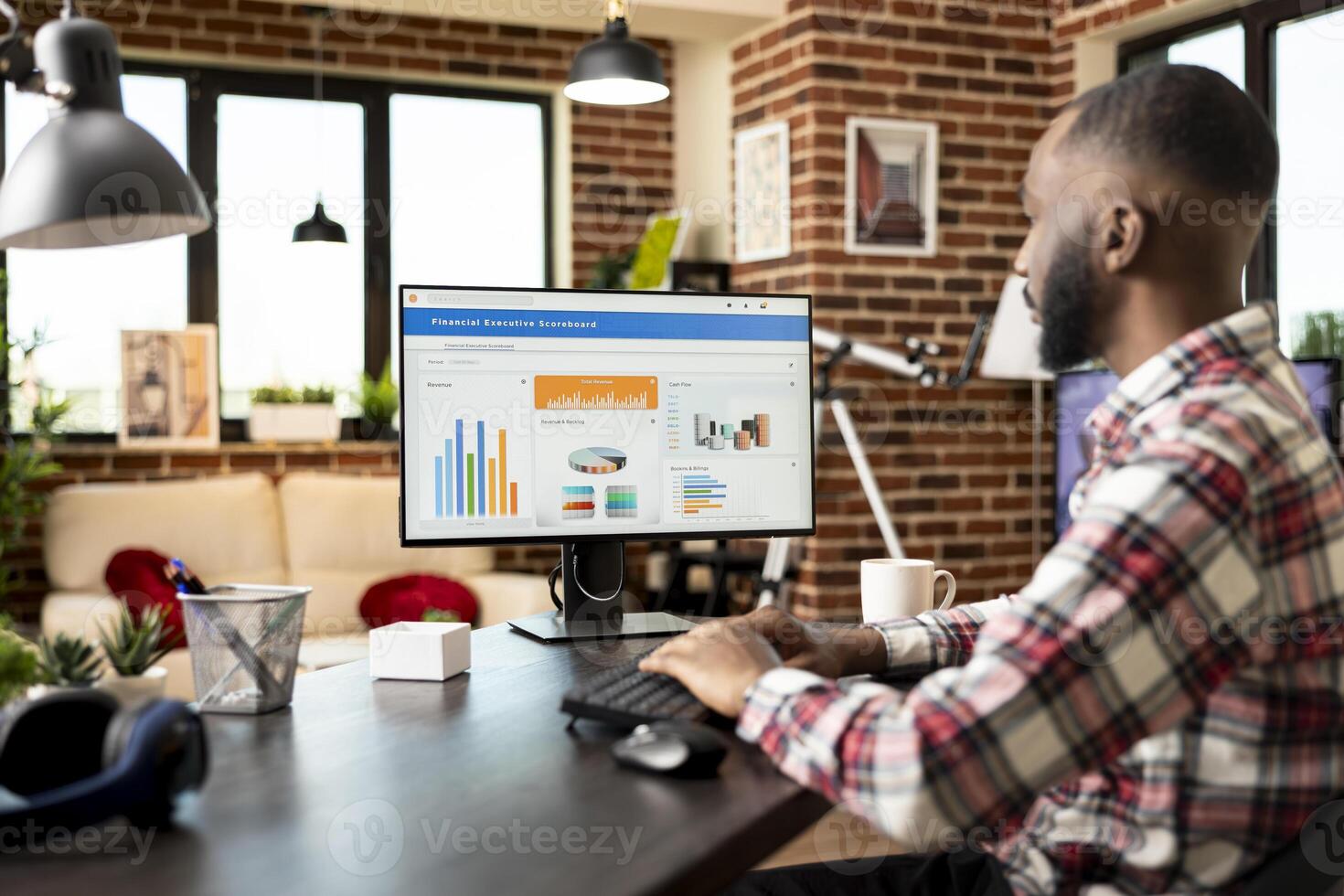 Remote male manager seated at home desk, organizing fiscal data and analyzing company progress report on computer. African american man formulates financial strategies for small business development. photo