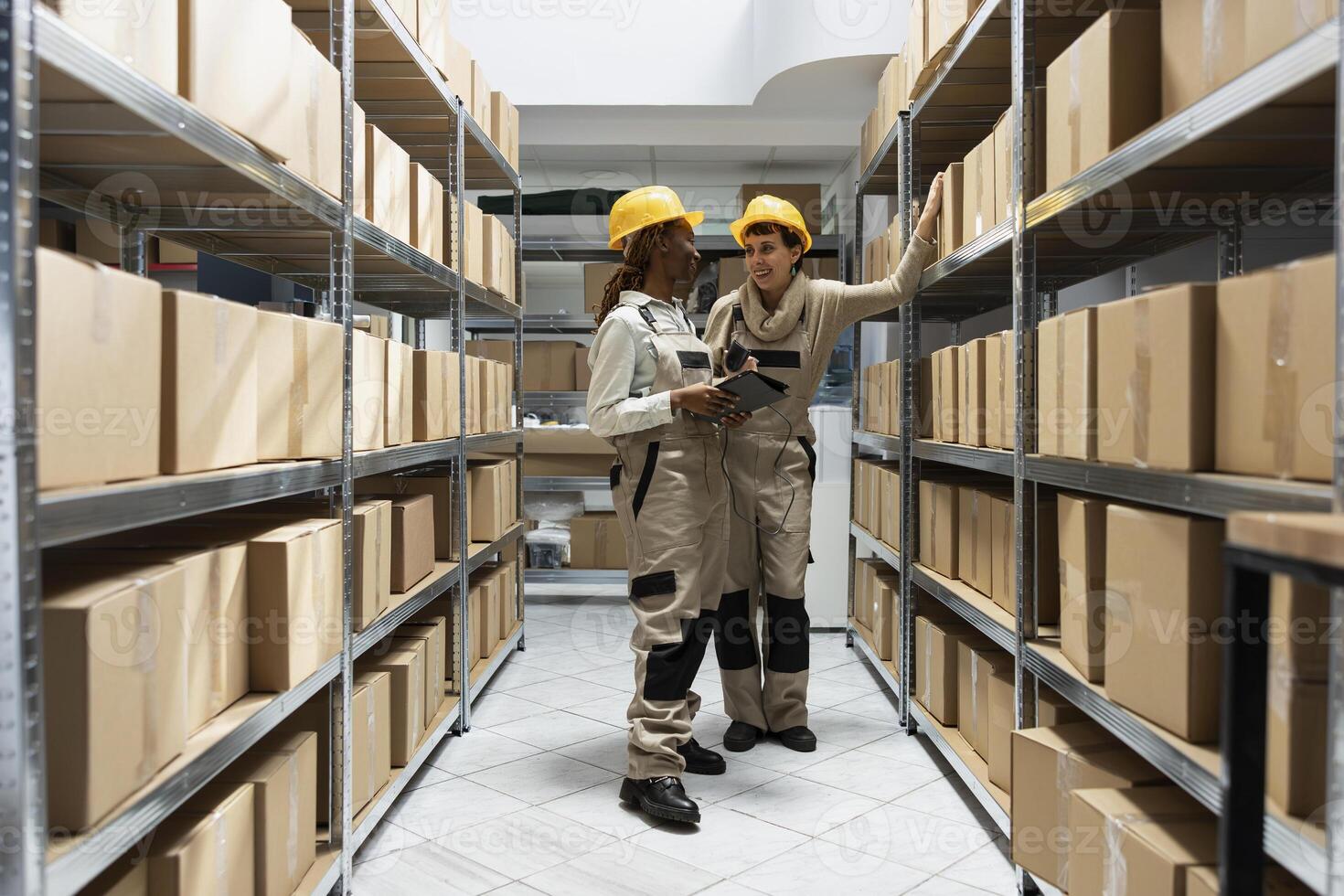 Multiethnic workers team tracking inventory using bar code systems, handling delivery crates for the order shipment. Factory workspace supports product storage and transportation logistics. photo