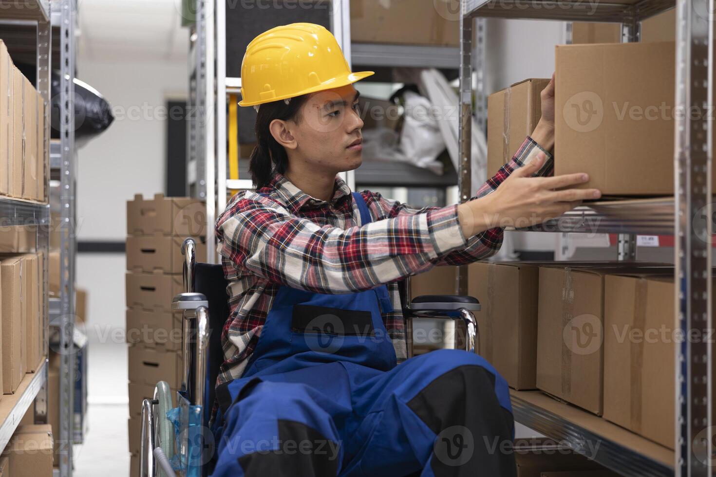 Asian employee with physical impairment processing parcels for local delivery, checking inventory and packages on depot racks. Storage room and shelves designed for accessibility. photo