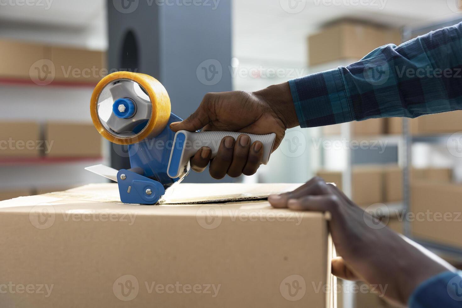 Factory worker applies adhesive tape to boxes while attaching air waybill and tracking numbers. African american staff manages packing, labeling and express delivery process in warehouse. photo