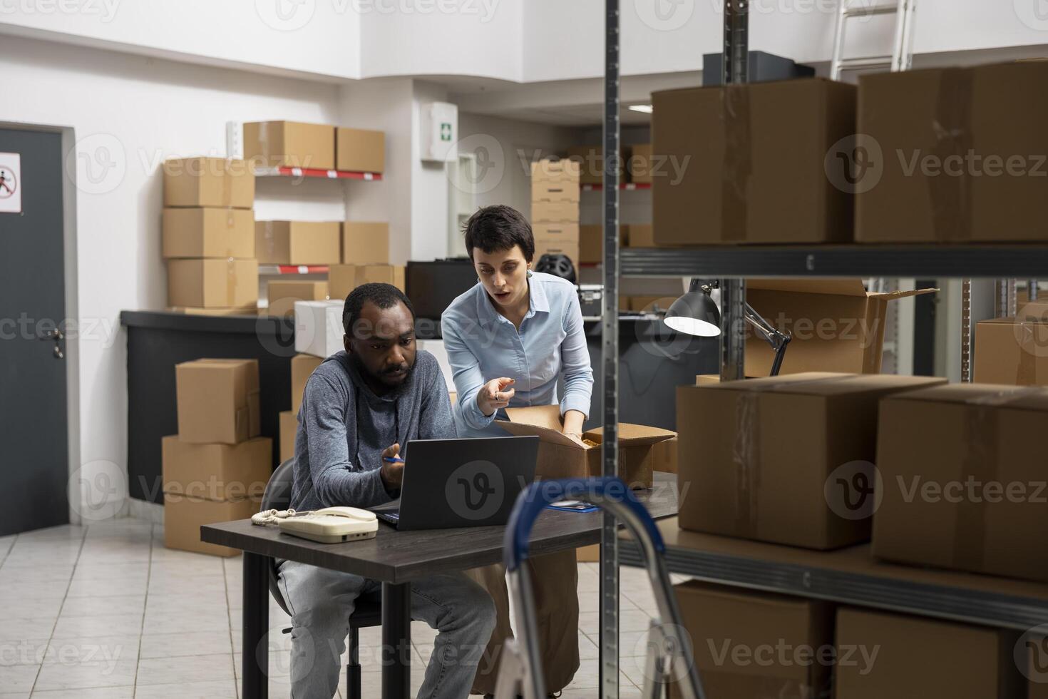 Multiethnic staff working on a local business express delivery with orders, surrounded by taped boxes and inventory shelves in a small warehouse. Industrial distribution logistics. photo