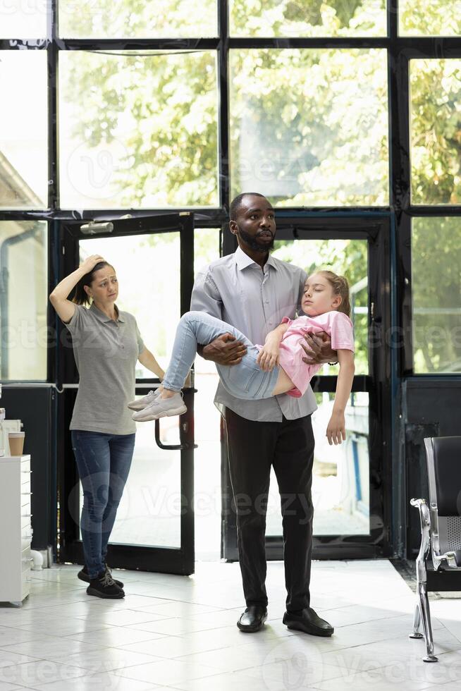 Young couple face pediatric medical crisis after daughter faints in lobby, asking for urgent support from black medical team in response to sudden collapse and serious health scare. photo
