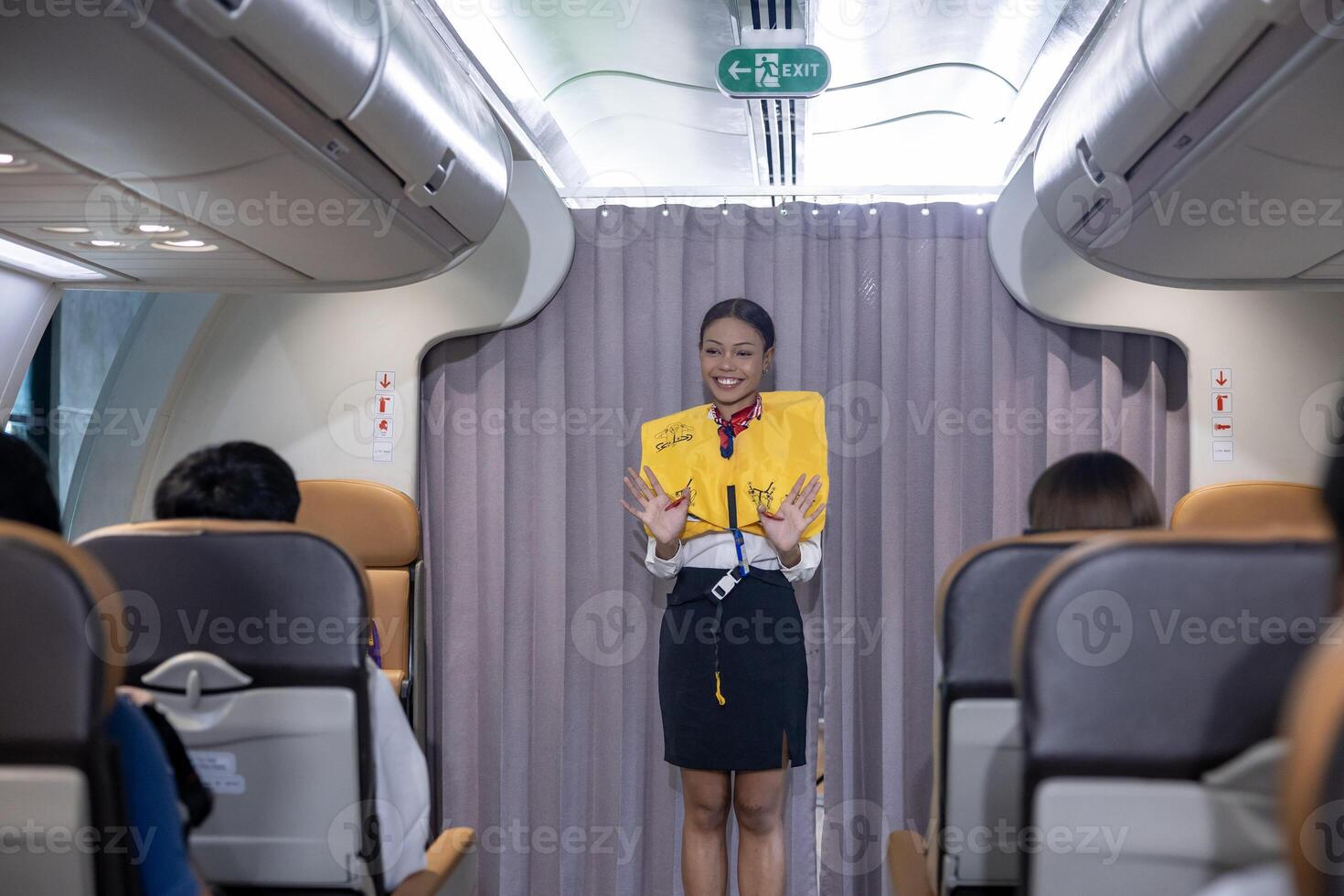 African flight attendant is demonstrating safety procedure using life jacket before taking off inside airplane for cabin crew and airline business photo
