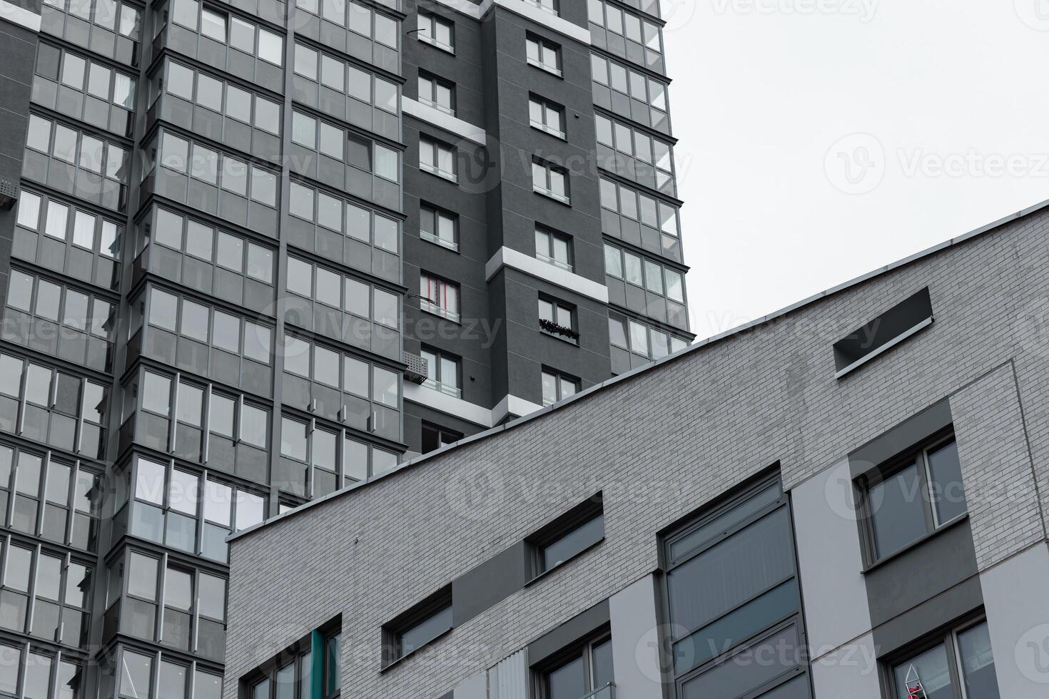 Architecture of tall modern apartment building. Urban highrise facade with geometric glass windows, photo