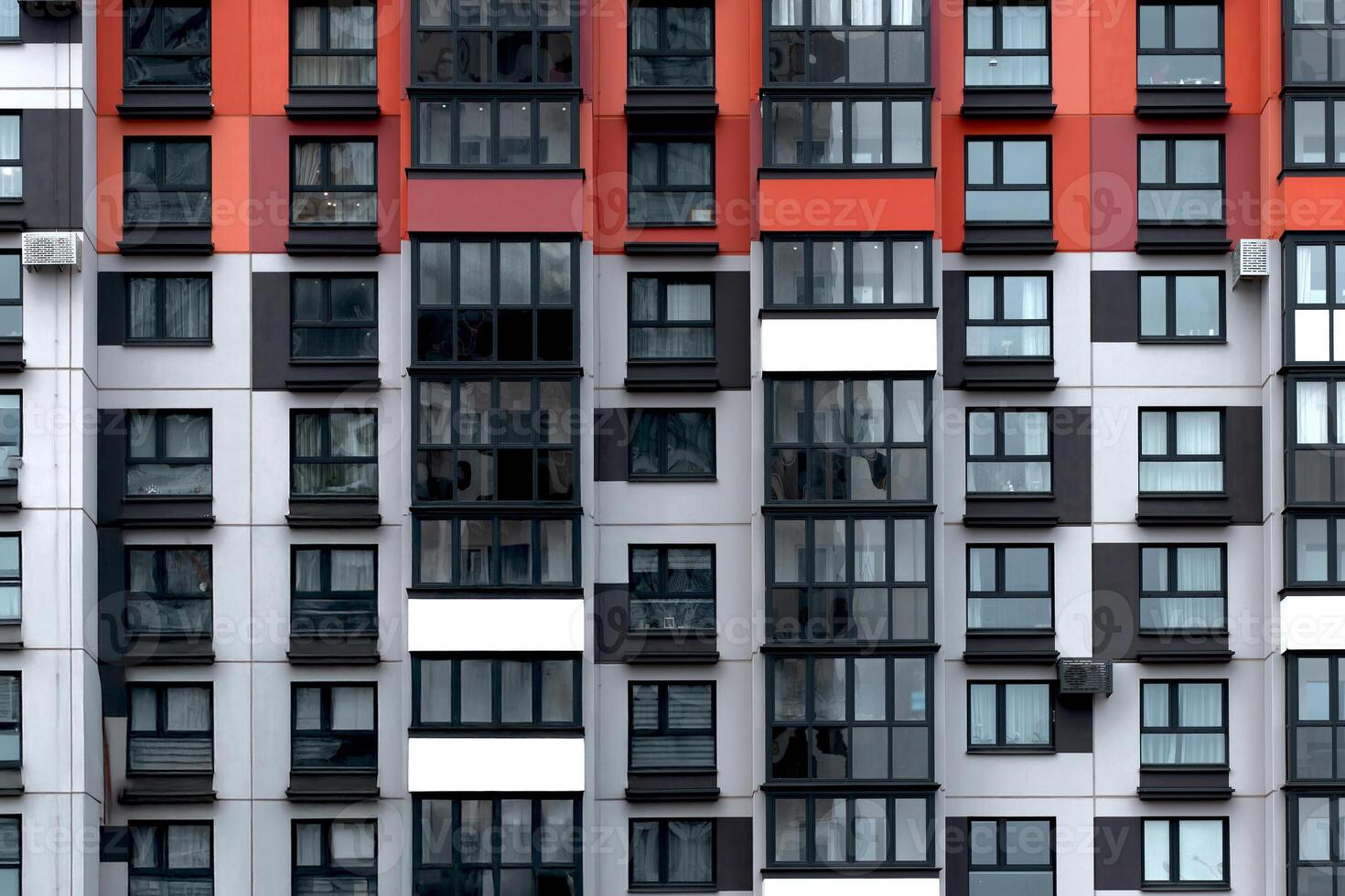 Building with red, black, and white apartment facade in geometric grid pattern. Modern modular photo