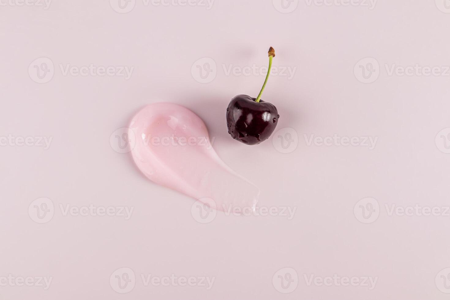 A chic sample of a cosmetic stroke of balm or a lip skin care mask on a pink background with ripe cherries. top view. cosmetic layout. A copy space photo
