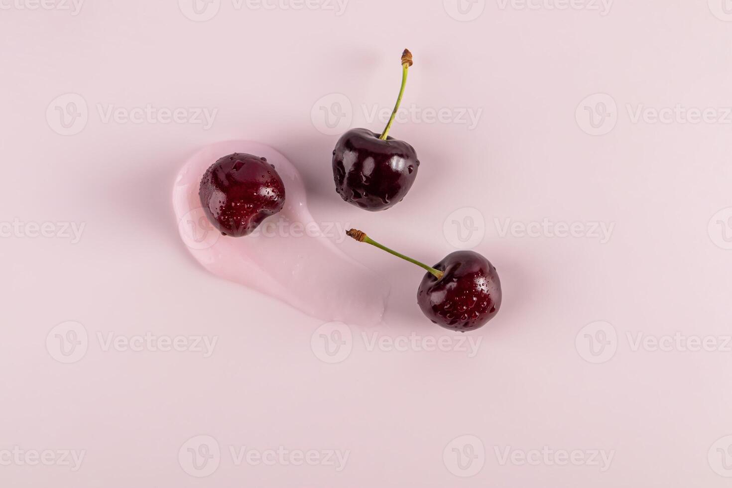 Beautiful brushstroke of cosmetic texture of balm, mask, lip gloss with ripe juicy cherries on pink background. top view. cosmetic layout. copy space. photo